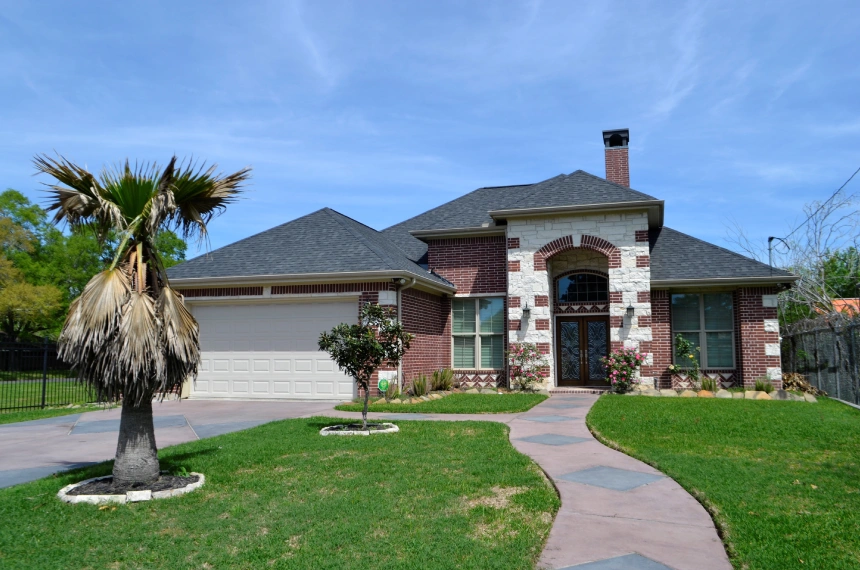 A house with a driveway and palm tree in front of it.