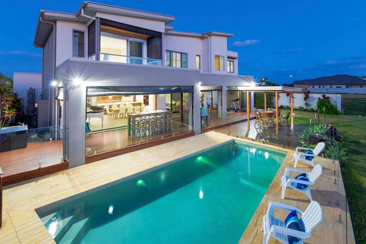 A large pool in front of a house at night.